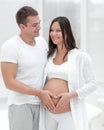 Husband and pregnant wife with folded hands in the shape of a heart on his tummy Royalty Free Stock Photo