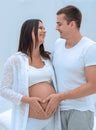 Husband and pregnant wife with folded hands in the shape of a heart on his tummy Royalty Free Stock Photo