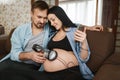 Husband and pregnant wife with headphones at belly