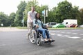 Husband rolls a wheelchair with a young wife