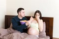 Husband tries to feed his pregnant wife with unhealthy snacks in bed but she refuses. Stop to the junk food during pregnancy