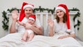 Husband and wife with baby waving hand in greeting on bed decorated Royalty Free Stock Photo