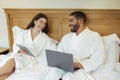 Husband And Wife Browsing Internet On Computers Sitting In Bedroom Royalty Free Stock Photo