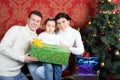 Husband, wife and daugther with gift smile near Christmas tree Royalty Free Stock Photo