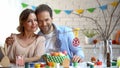 Husband and wife looking at toy eggs on tree-branch, preparing Easter decoration Royalty Free Stock Photo