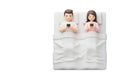 Husband and wife lying in bed with smartphones. Space for text. Royalty Free Stock Photo