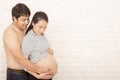 Husband and wife in pregnancy. Portrait of happy pregnant woman and husband smile. Brick background. Space for text