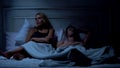 Husband and wife quarreling in bed, not looking at each other, family problems Royalty Free Stock Photo