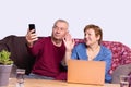Husband and wife are sitting in front of computer with two glasses of water at the table and talking online on the Royalty Free Stock Photo