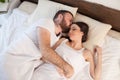 Husband and wife are sleeping in beds with white linen