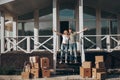 Husband and wife standing in front of new buying home with boxes