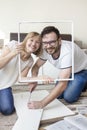 Husband and wife are twisting furniture in the living room. Smiling people pose for a photo with a desk element as a photo frame.