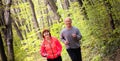 Husbanf and wife wearing sportswear and running in forest Royalty Free Stock Photo