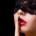 Hush. woman with finger on her red lips showing shush. Erotic girl with lace mask over black