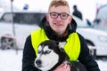 Husky dog hugs with young guy. Winter outdoor walking - Reshetiha, Russia - 02.02.2019