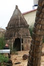 A hut made of reeds by the native indians of Lake Titicaca with a stone house in the background in Peru, South America Royalty Free Stock Photo