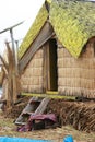 A hut with a yellow roof made of reeds by the native indians that is standing in a man made island at Lake Titicaca in Peru, South Royalty Free Stock Photo