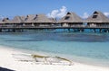 Huts on water in the sea and a small white boat on the shore Royalty Free Stock Photo