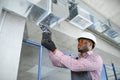 hvac african worker install ducted pipe system for ventilation and air conditioning. copy space