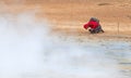 Woman photographing near a steaming fumarole in geothermal area of Hverir, Iceland