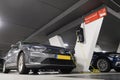 Hybrid car at charging station in underground parking with power supply point