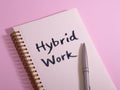 Hybrid work concept on spiral notebook with pen on pink background Royalty Free Stock Photo