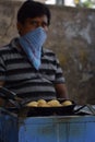 Hyderabad, Telangana, India. july-20-2020: indian street food maker preparing ponganaalu while wearing face mask, tasty food,