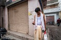 An Indian man in traditional attire of a dhoti, a white vest and a stole standing outside a