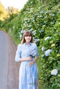 Hydrangea gardening. Portrait of young beautiful woman in long blue dress in magic blooming park in Sao Miguel, Azores