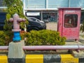 Hydrant pillar and hydrant box wit faded red paint, in front of office building