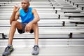 Hydrating while contemplating his next run. Full length shot of a male athlete sitting on the rafters at the track and Royalty Free Stock Photo