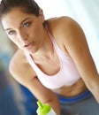 Hydration is key. A beautiful young woman sitting at the gym taking a break and having a drink of water. Royalty Free Stock Photo