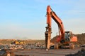 Hydraulic breaker hammer for the destruction of concrete and hard rock at the construction site. Excavator on sunset background. Royalty Free Stock Photo