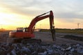 Hydraulic breaker hammer for the destruction of concrete and hard rock at the construction site. Excavator on sunset background. Royalty Free Stock Photo