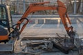 Hydraulic crawler excavator with black-orange cab, orange three-part digging mechanism with bucket, standing on repair site