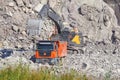 The hydraulic crawler excavator and orange truck at work in a quarry.