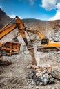 Hydraulic crusher and track type excavator backhoe machinery working. Industrial machineries working on open pit mine, ore quarry