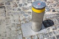 Hydraulic gray electric bollard with a yellow reflective strip. Royalty Free Stock Photo