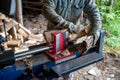 Hydraulic log splitter blade cuts into wood with workman and woodpile Royalty Free Stock Photo