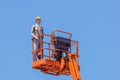 Hydraulic mobile construction platform elevated towards a blue sky with false construction workers . dummy man Royalty Free Stock Photo