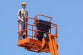 Hydraulic mobile construction platform elevated towards a blue sky with false construction workers . dummy man Royalty Free Stock Photo