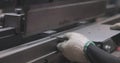 Hydraulic sheet metal bending machine. A worker bends a metal part in a machine. Metal processing