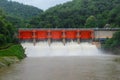 Hydro dam structure with open gates releasing muddy flood water Royalty Free Stock Photo