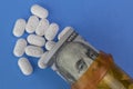 Hydrocodone tablets with Benjamin Franklin on a hundred dollar bill and a pill bottle.