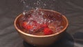 Hygenic Cherry Tomatoes falling to the water in wooden bowl