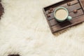 Hygge still life with hot cup of black coffee, warm scarf on furskin and wooden board. View from above