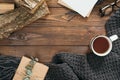 Hygge style flatlay frame of blank paper card, cup of tea, fashion knitted scarf, gift box, firewood on wooden background. Flat