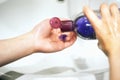 Hygiene. Close-up of a woman pouring some colored liquid soap on her hands in the bathroom. A young girl washes her hands..