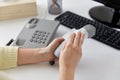 Close up of woman cleaning desk phone with tissue
