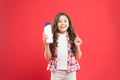 Hygiene habits for kids. Happy little girl holding gel or shampoo bottle for personal hygiene on red background. Small Royalty Free Stock Photo